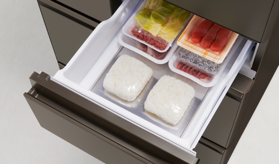 三菱の瞬冷凍室の引き出しを開けた写真。ラップで包んだご飯や肉・野菜がトレイに並べて入れられている。